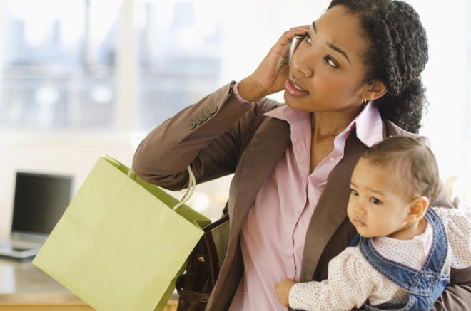 Mixed race woman holding baby and talking on cell phone